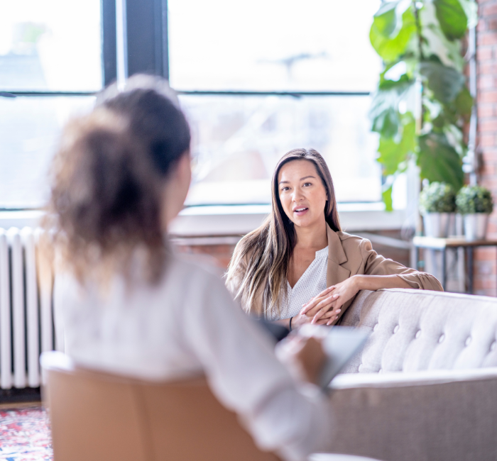 woman sitting on a couch speaking to a therapist.