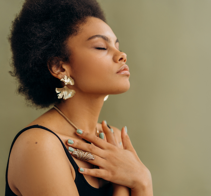 a woman holding her hands in her heart with her eyes closed.