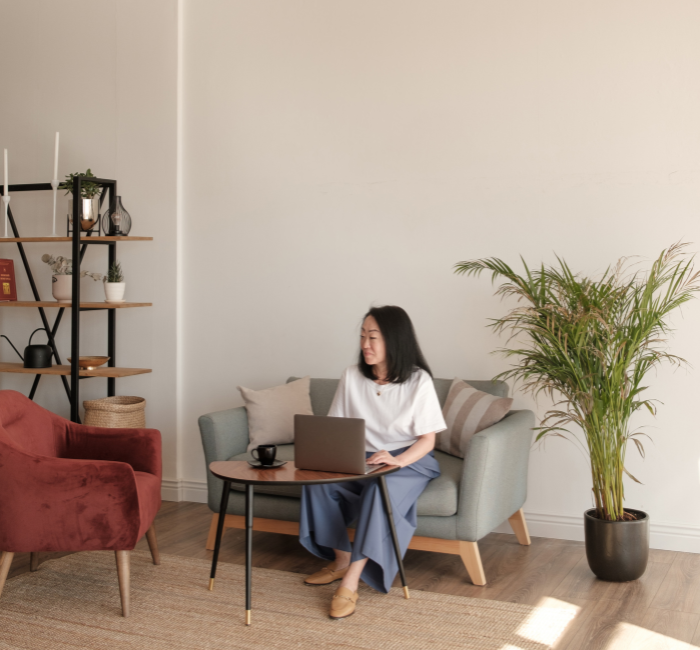 woman sitting on couch and typing on laptop